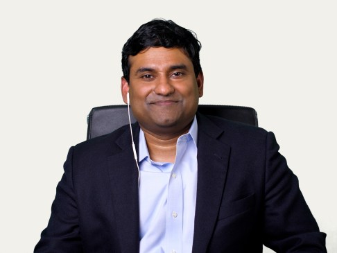 man in suit sitting in a black chair with a white background