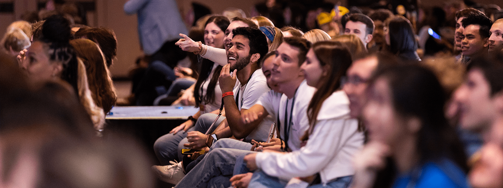 Group of students watching the stage at AMA's ICC event. The students are laughing and enjoying the speaker on stage.